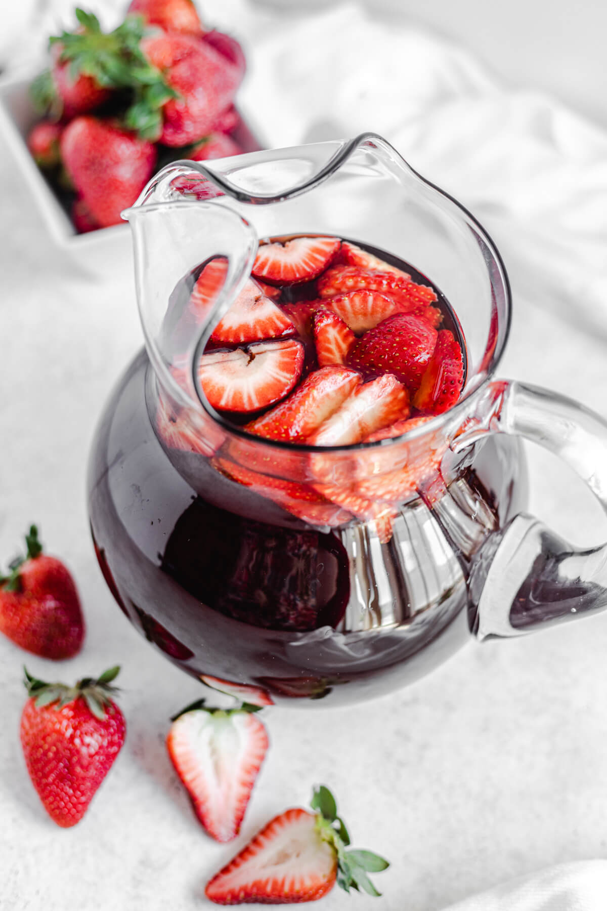 glass pitcher of iced tea with fresh sliced strawberries inside
