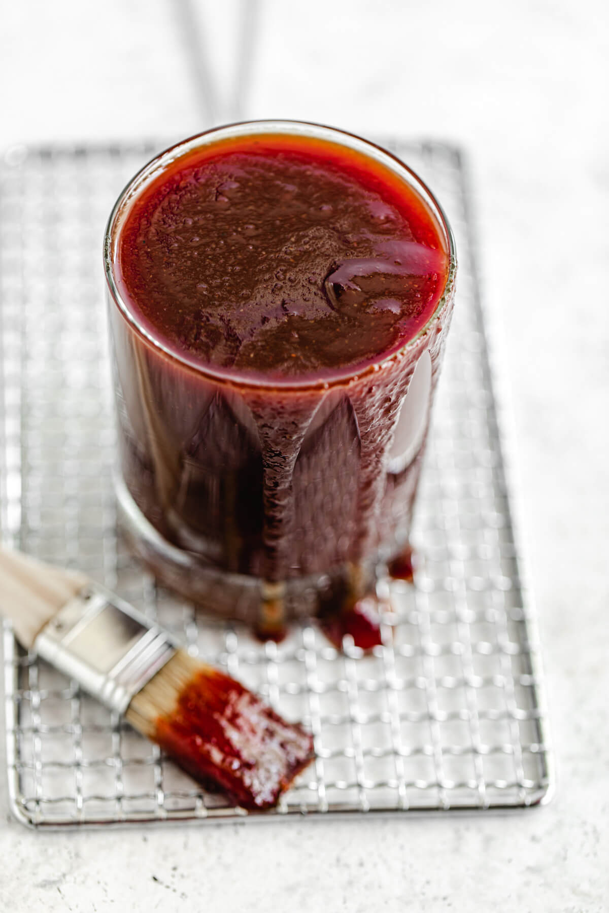 glass of bbq sauce on a safety grater with a dipped pastry brush beside it