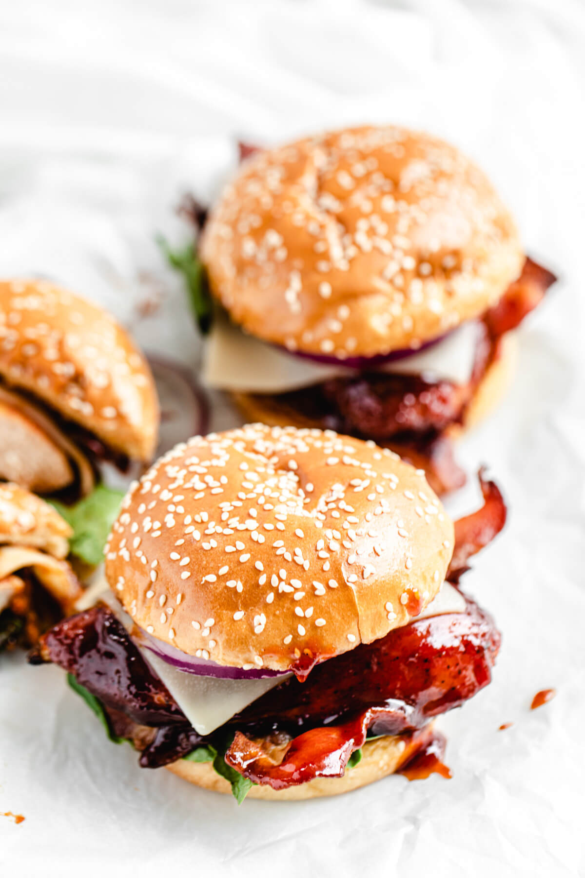 three chicken sandwiches on a white platter with one of the sandwiches cut in half