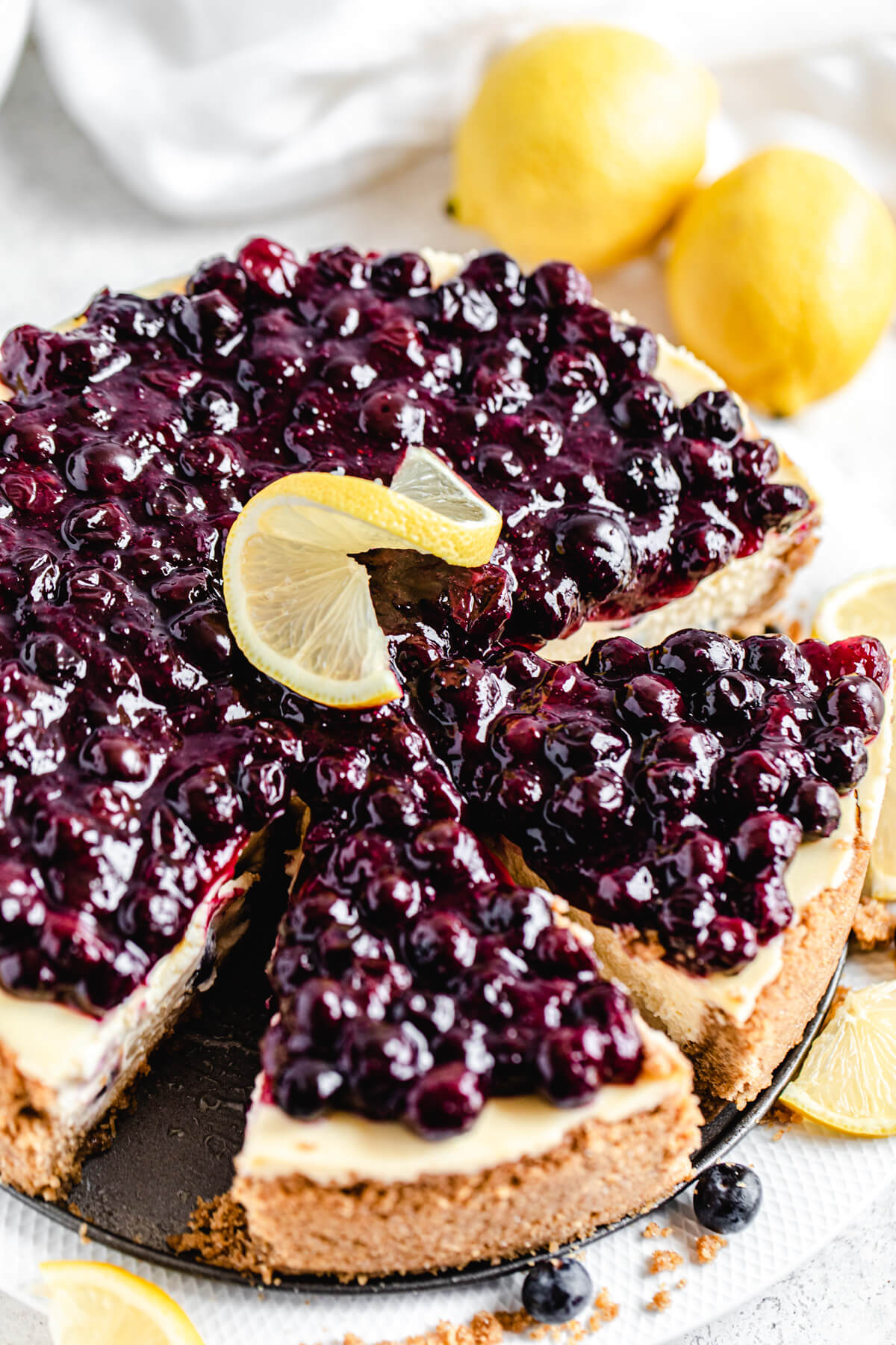 close up of sliced cheesecake with two lemons behind it