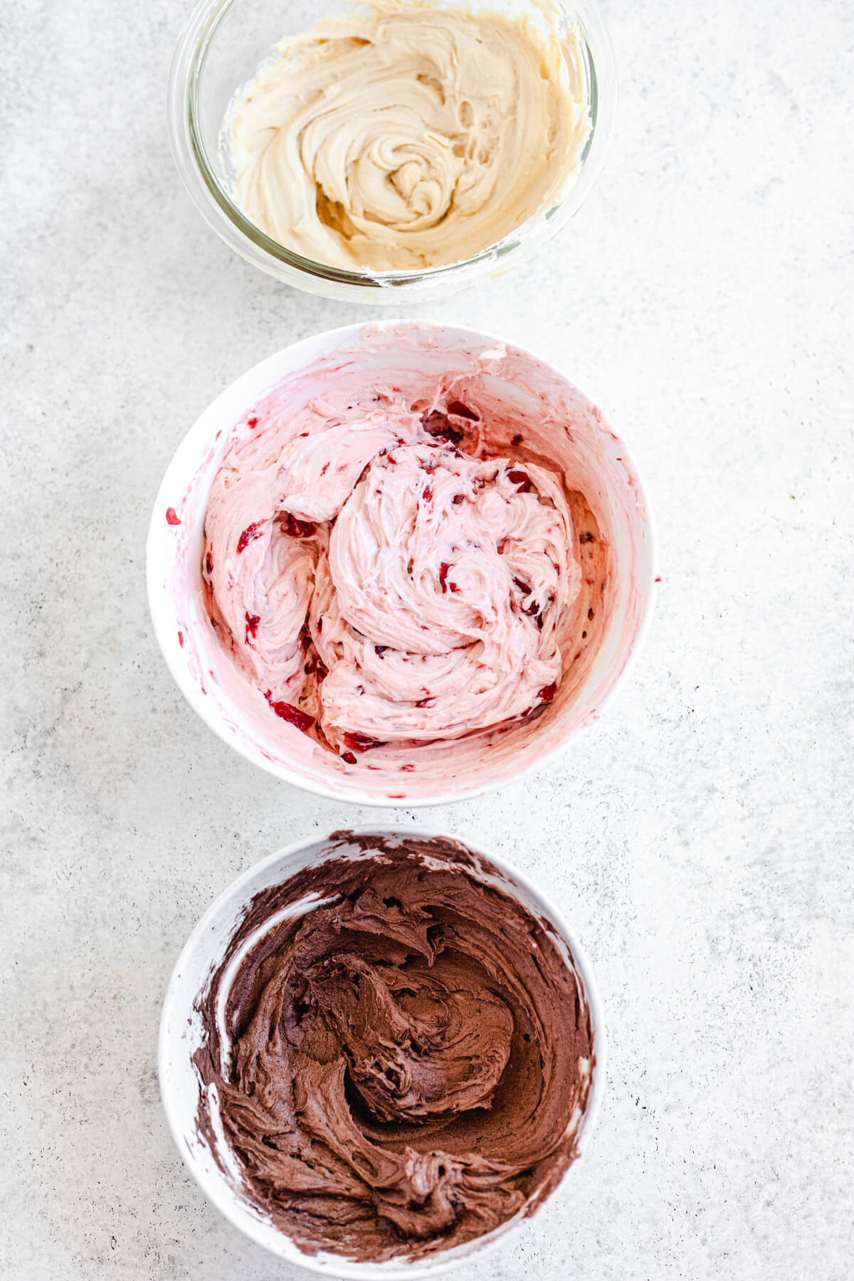 chocolate, strawberry and caramel frosting in three bowls