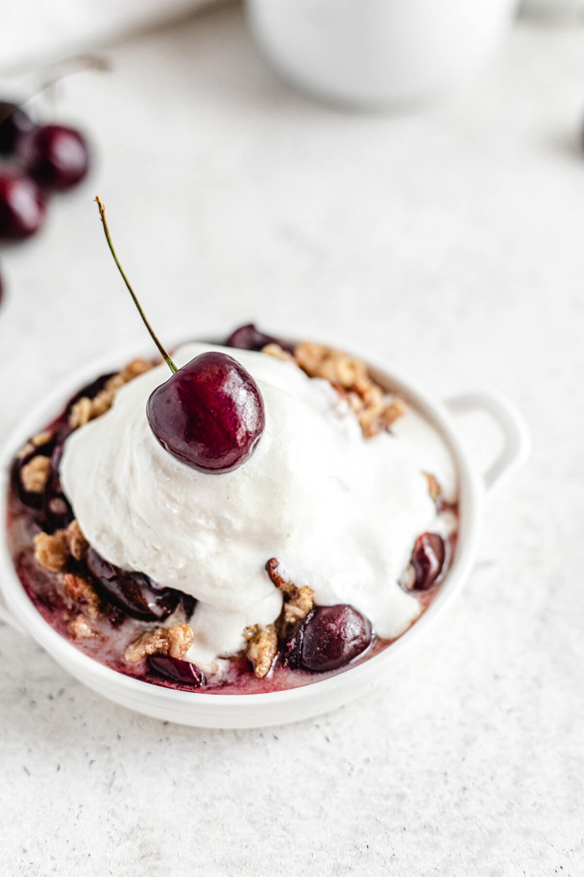 close up of crumble with melting scoop of vanilla and a cherry on top