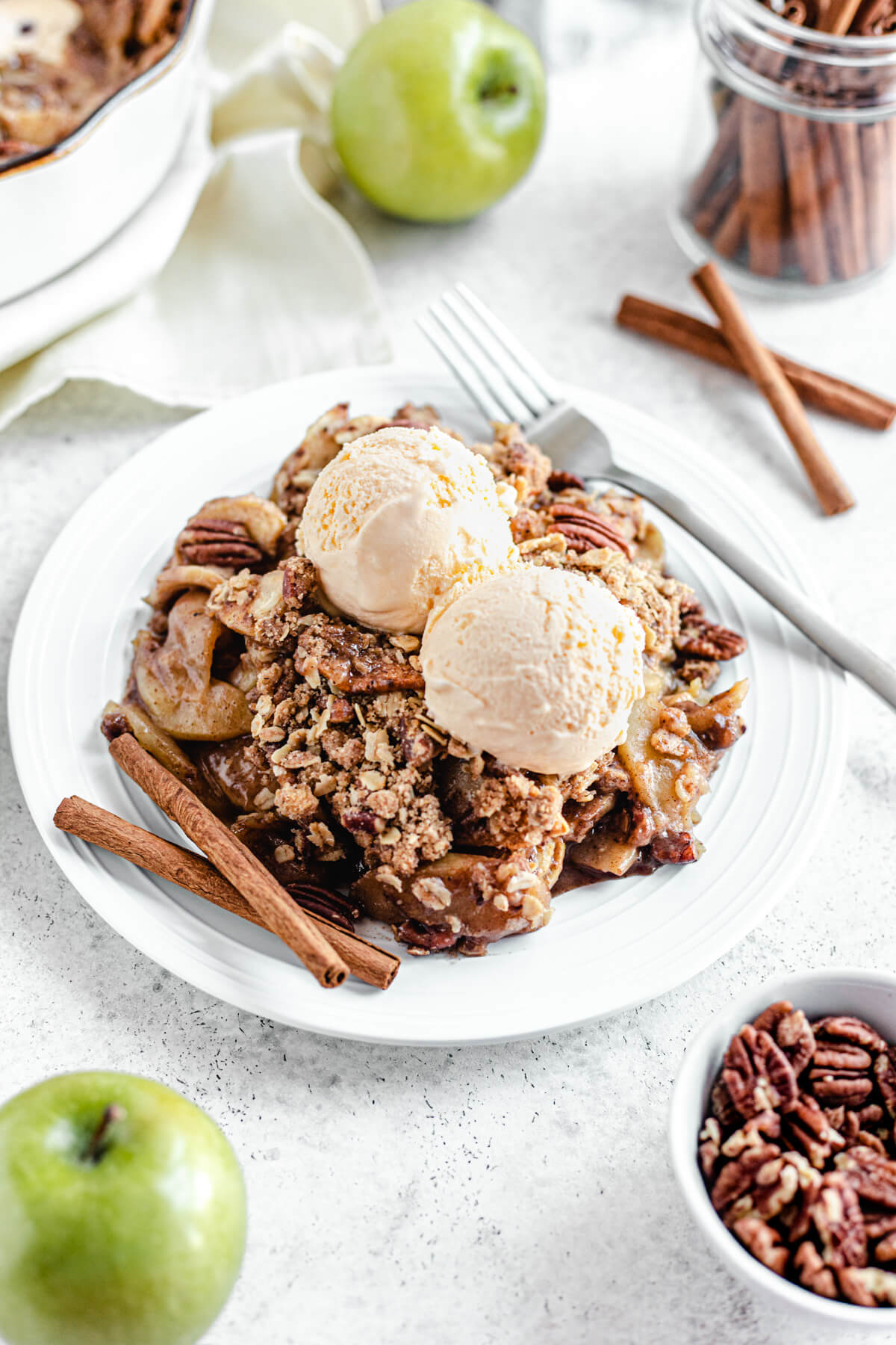 apple crisp in a white plate topped with two scoops of ice cream