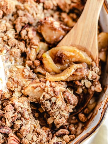 close up of apple crisp with wooden spoon digging in