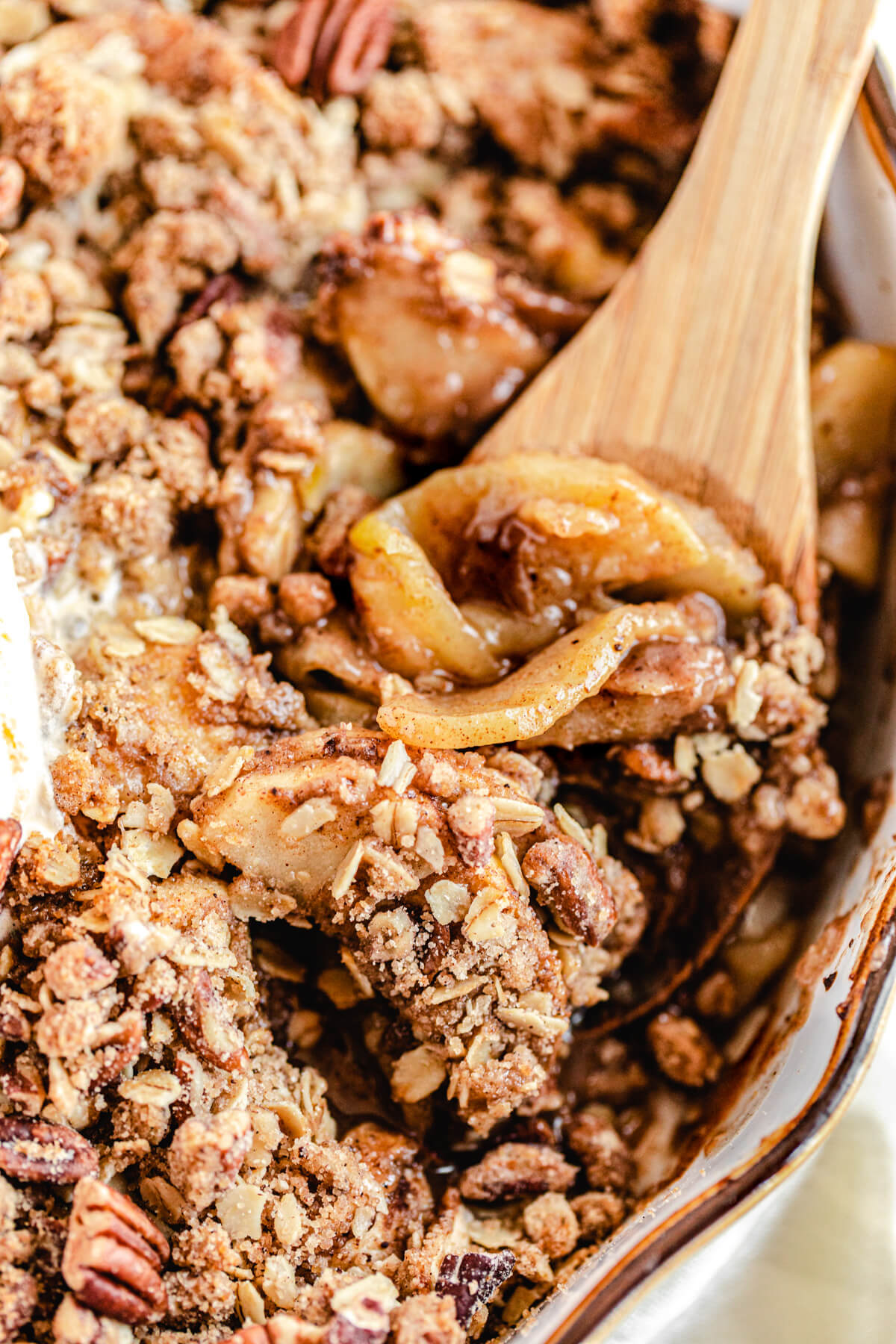 close up of apple crisp with wooden spoon taking a scoop out