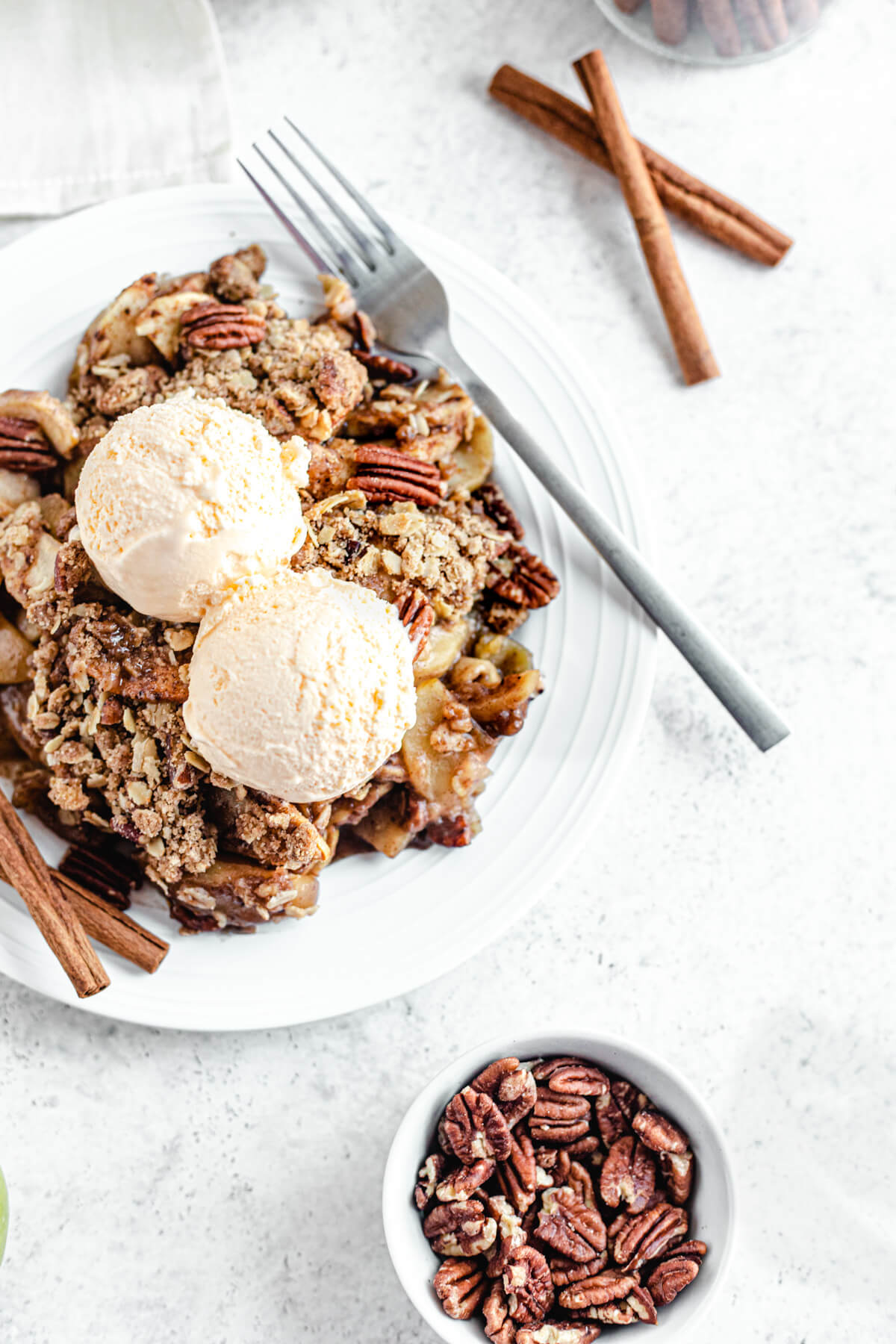 close up of apple crisp in a plate topped with ice cream