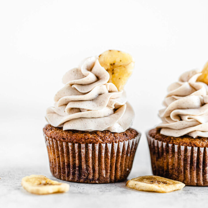 two banana cupcakes side by side with two banana chips beside them
