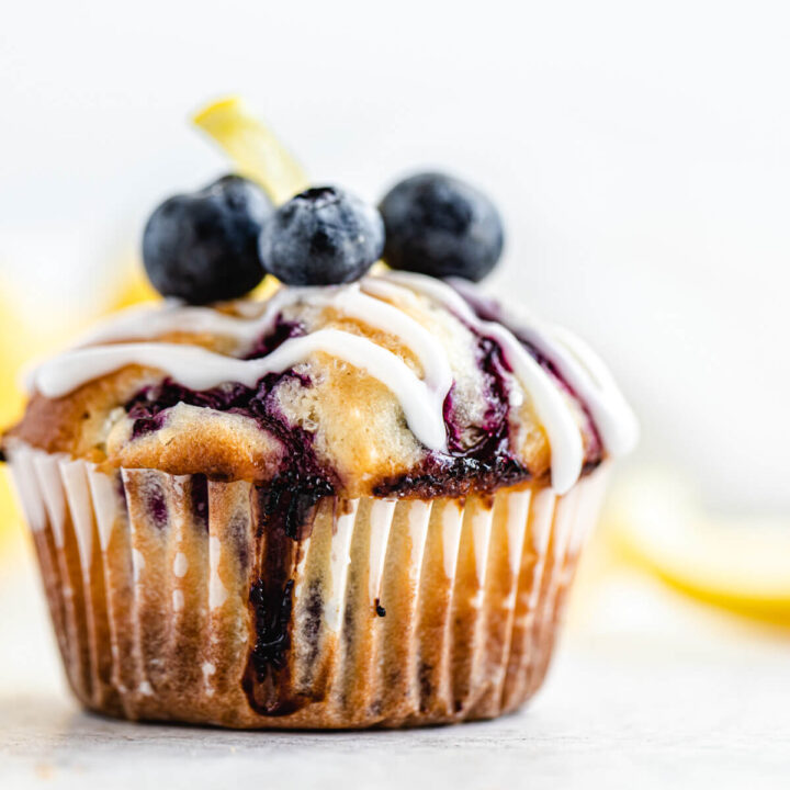 close up of muffin topped with lemon glaze and fresh blueberries