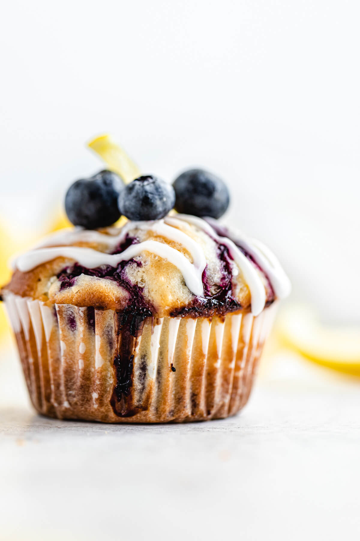 close up of muffin topped with lemon glaze and fresh blueberries