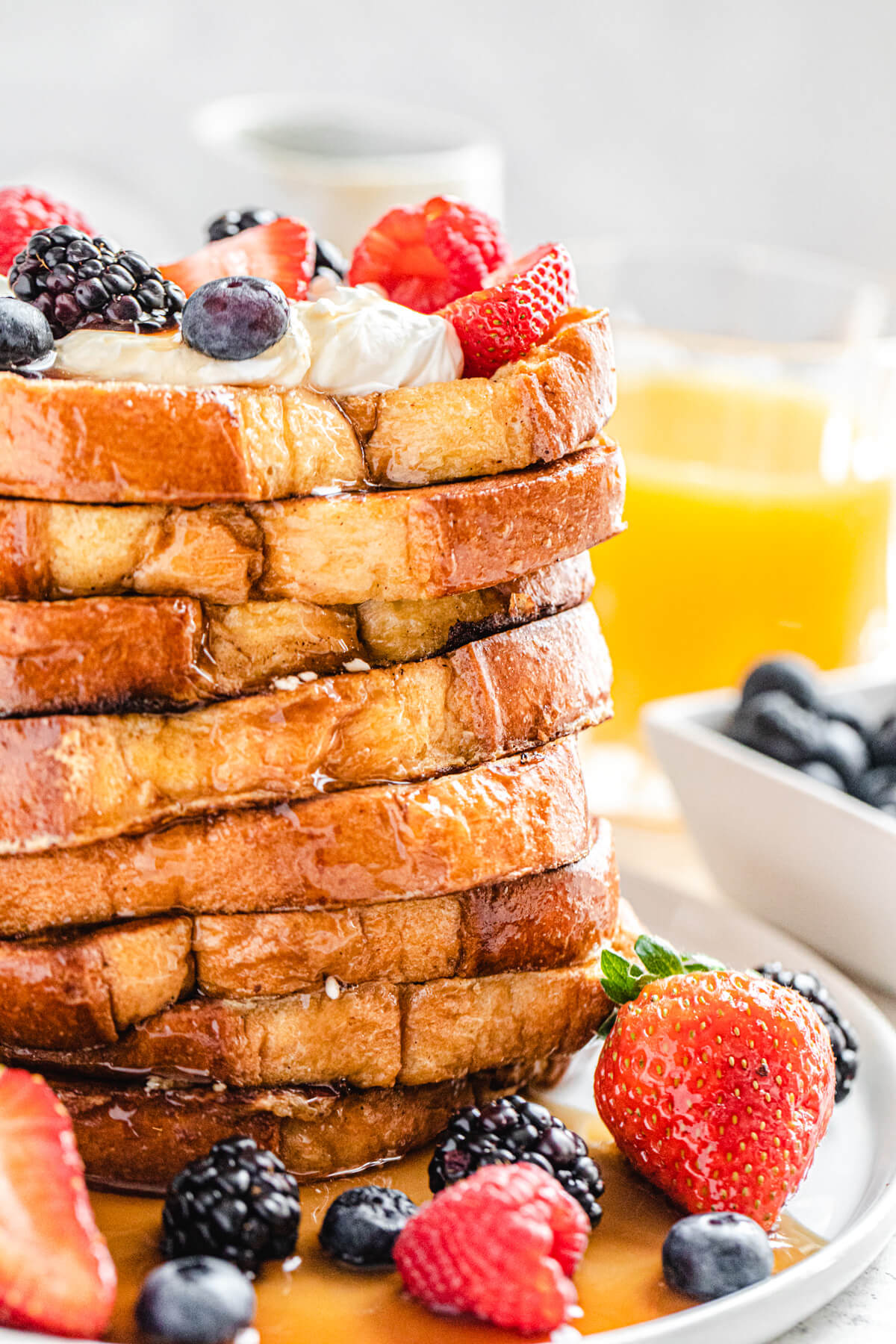 tall stack of French toast topped with whipped cream and fresh fruit