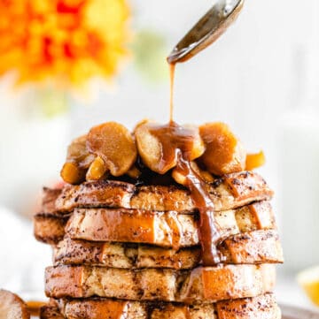 close up spooning syrup onto a stack of French toast on a plate