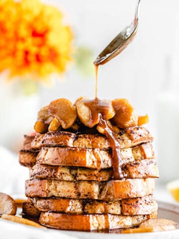 close up spooning syrup onto a stack of French toast on a plate