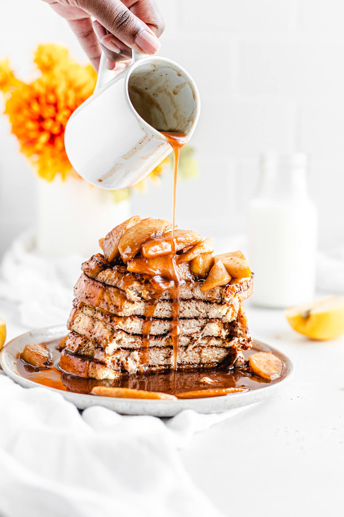 pouring syrup onto sliced stack of French toast 