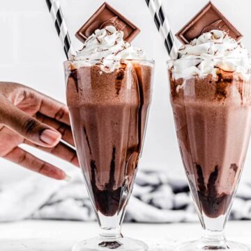 reaching for 1 of 2 chocolate milkshakes on a rectangle board