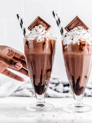 reaching for 1 of 2 chocolate milkshakes on a rectangle board