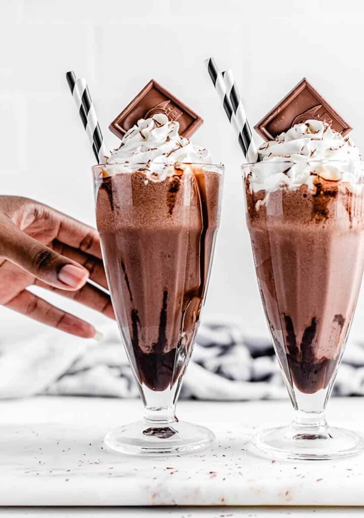 reaching for 1 of 2 chocolate milkshakes on a rectangle board