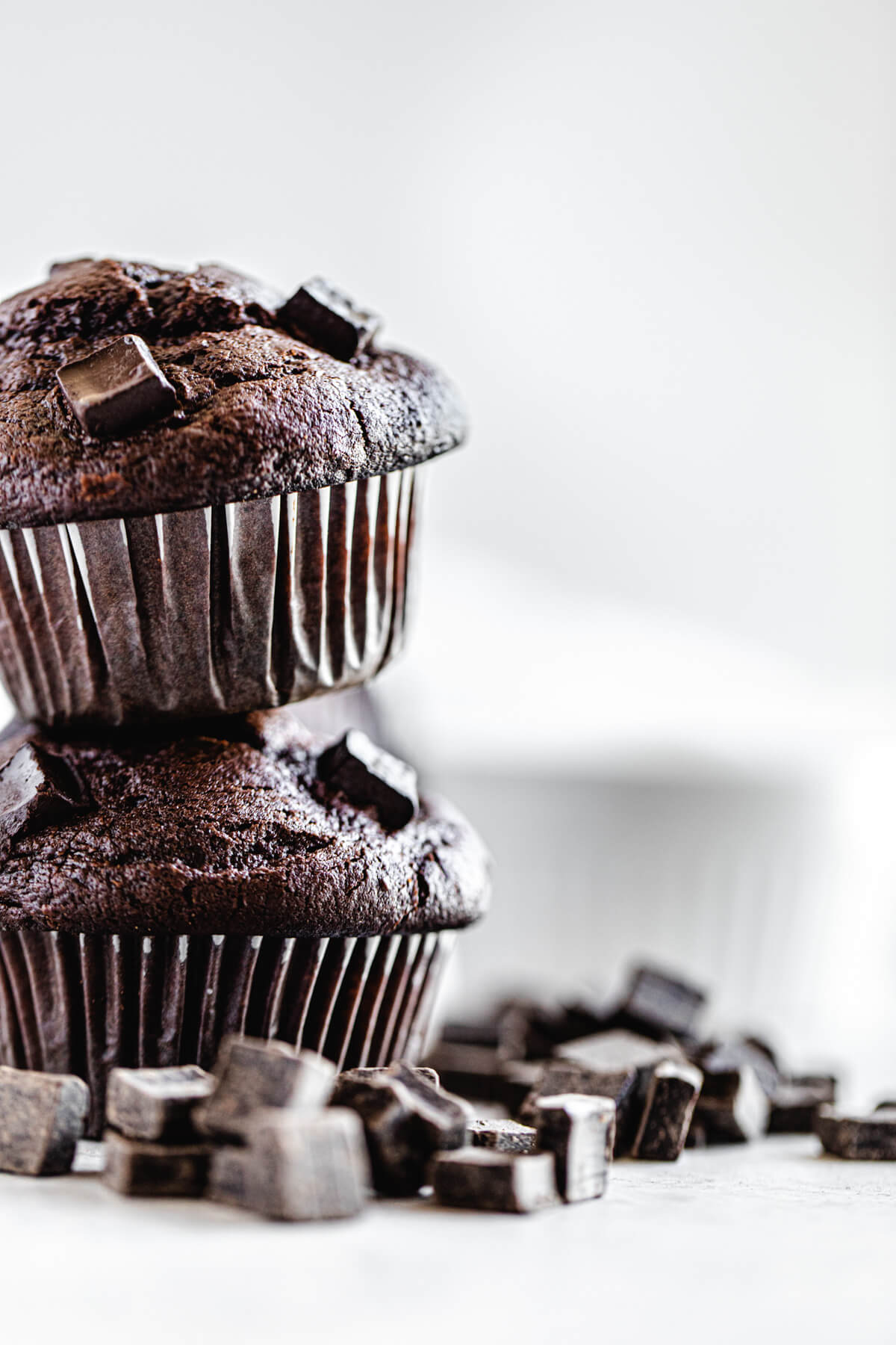 two muffins stacked with chocolate chunks surrounding them