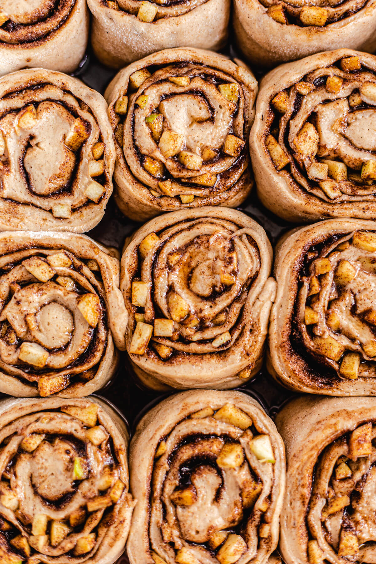 close up of unbaked apple filled cinnamon rolls in a dish