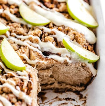 close up of cinnamon rolls in a dish with front roll removed