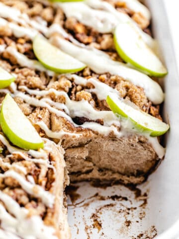 close up of cinnamon rolls in a dish with front roll removed