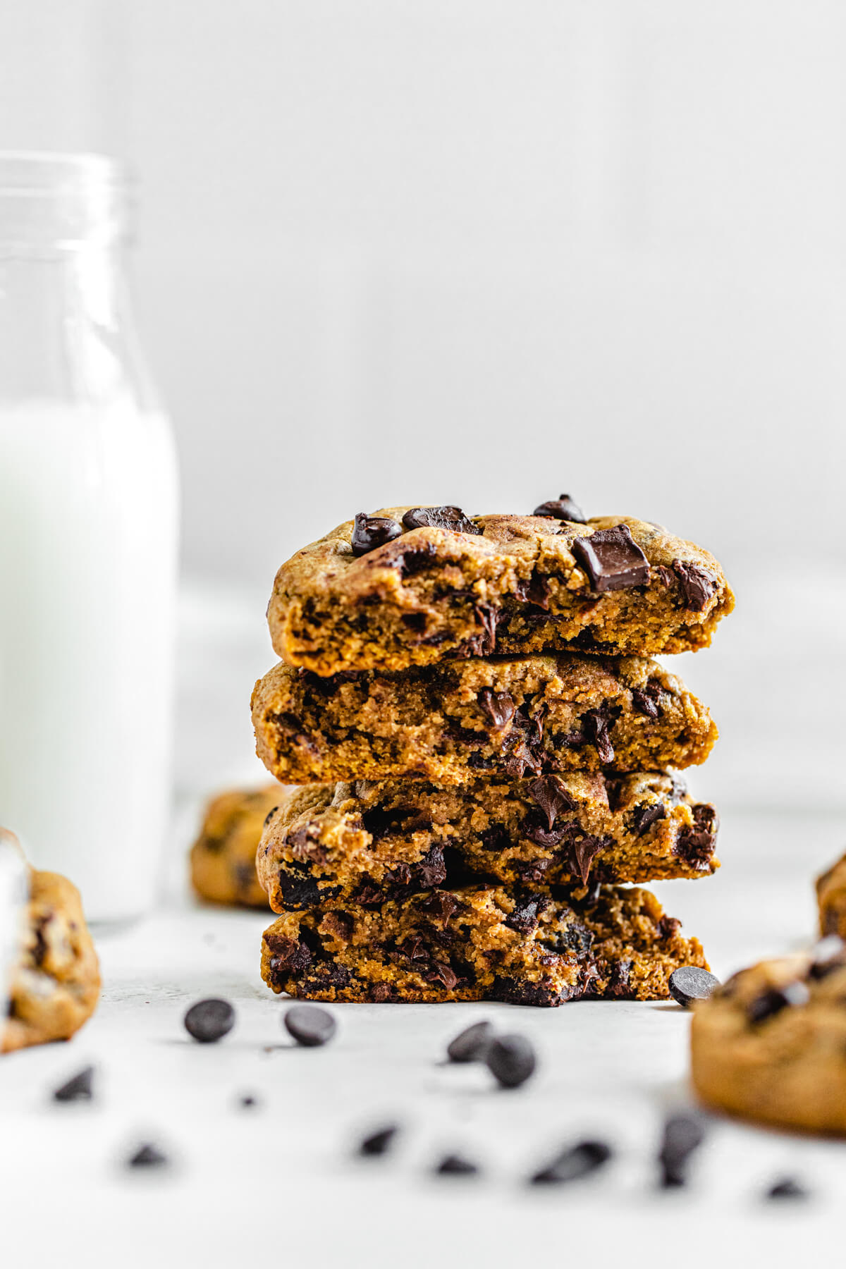 stack of halved chocolate chip cookies next to a bottle of milk