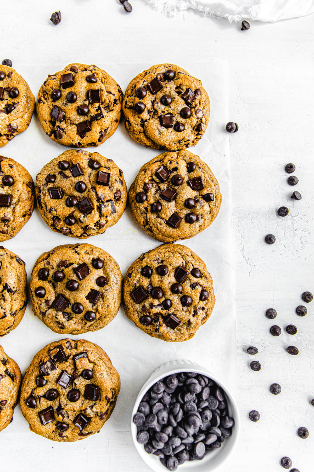 overhead of cookies lined up in rows with a ramekin of chocolate chips at the bottom