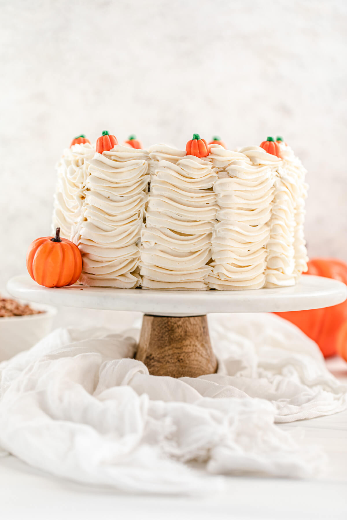 cake on a cake stand with a small pumpkin beside it