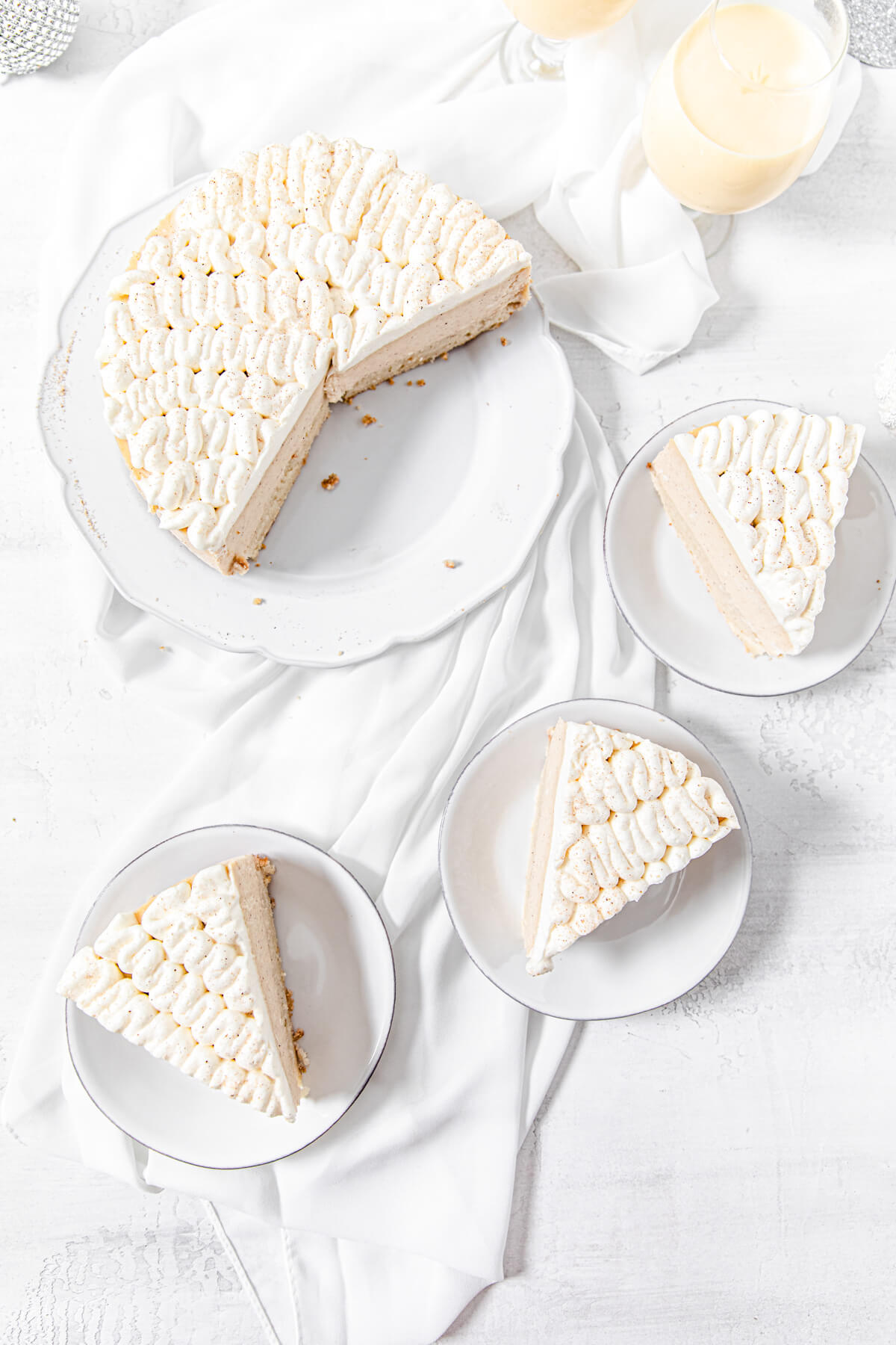 top view of cheesecake on a platter with three slices in three small white plates