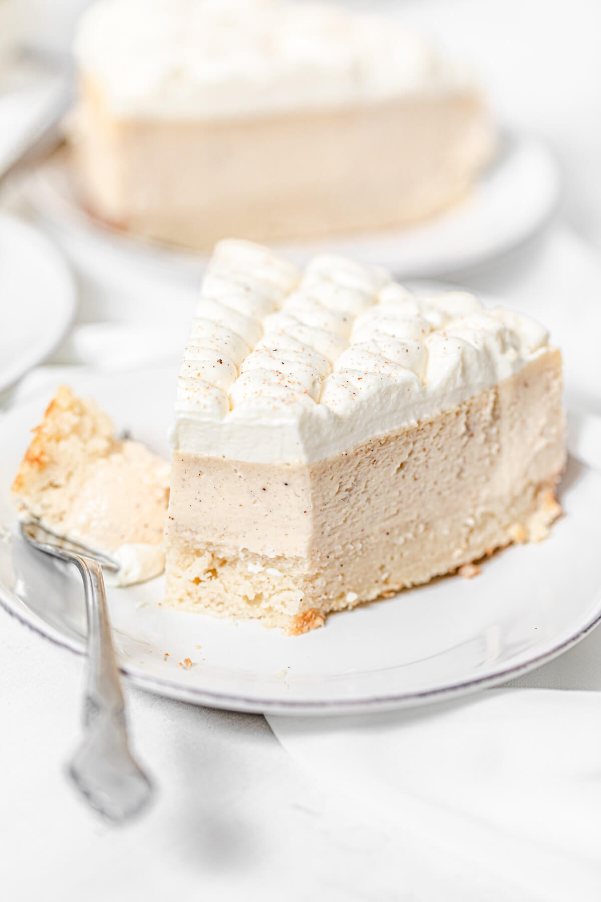 half eaten cheesecake on a small white plate with a fork next to it