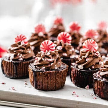 mini cheesecakes on a baking sheet with candy canes in the background