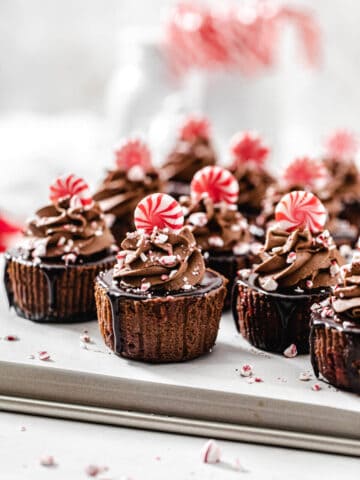 mini cheesecakes on a baking sheet with candy canes in the background