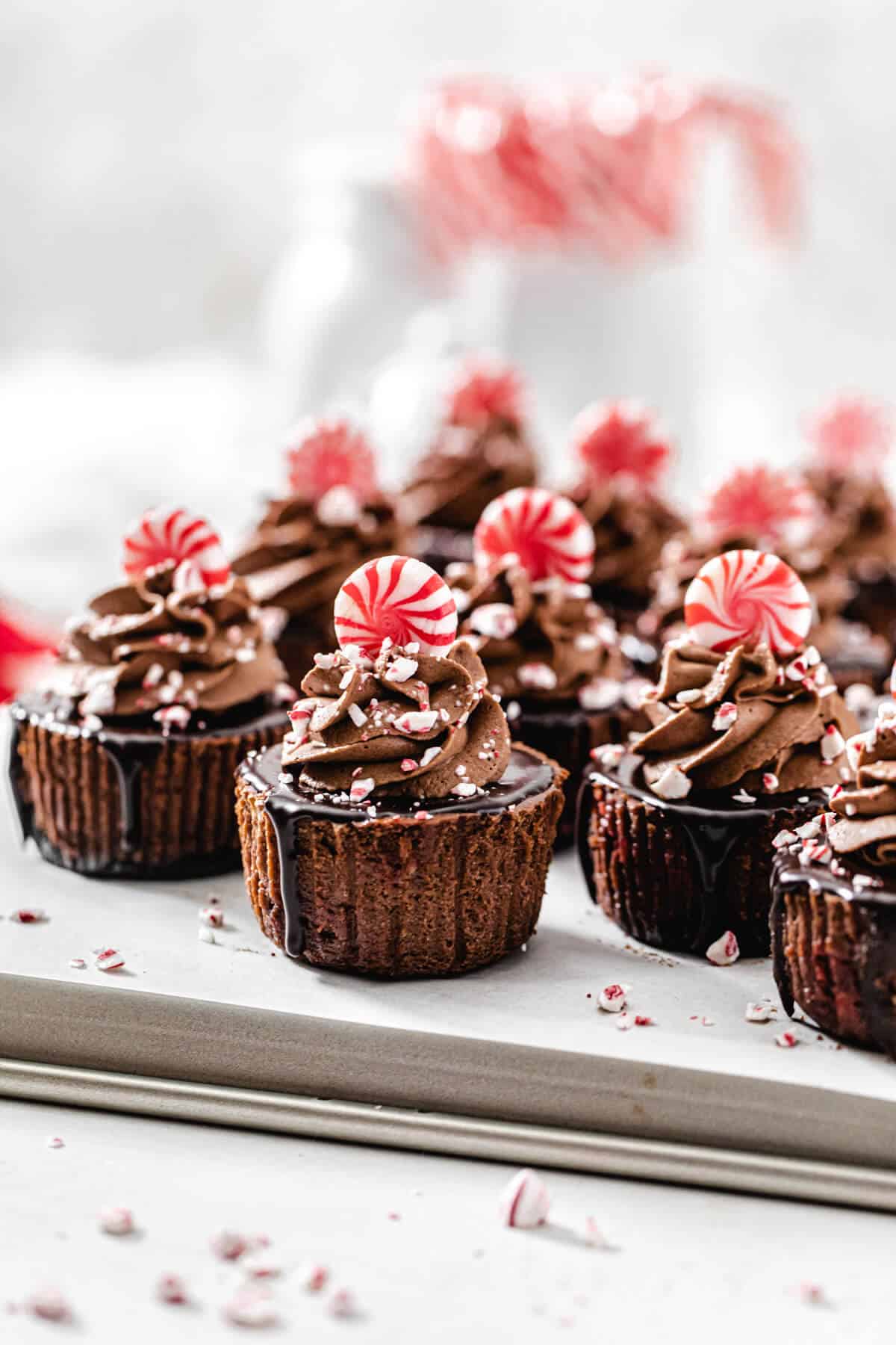 mini cheesecakes on a baking sheet with candy canes in the background