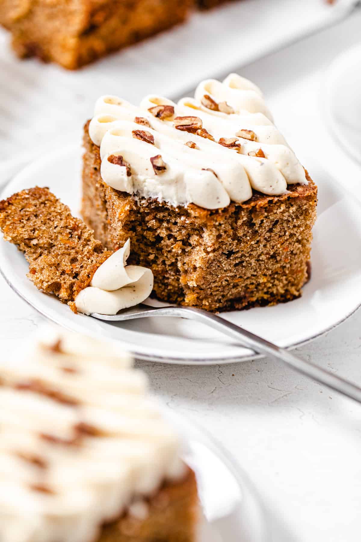 slice of cake on a small plate with a fork bite taken out of it