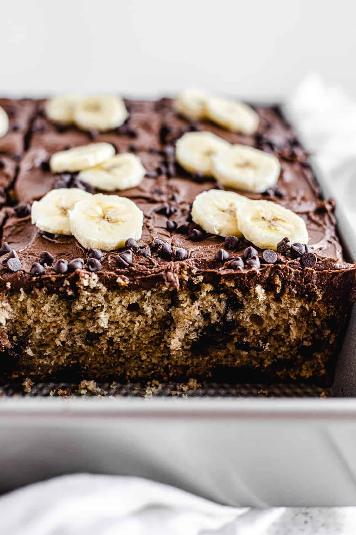 cake topped with chocolate frosting and banana slices in a rectangular cake pan