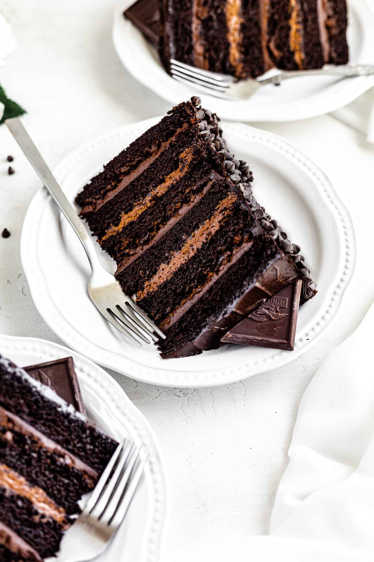 three slices of cake on white plates with a fork beside it