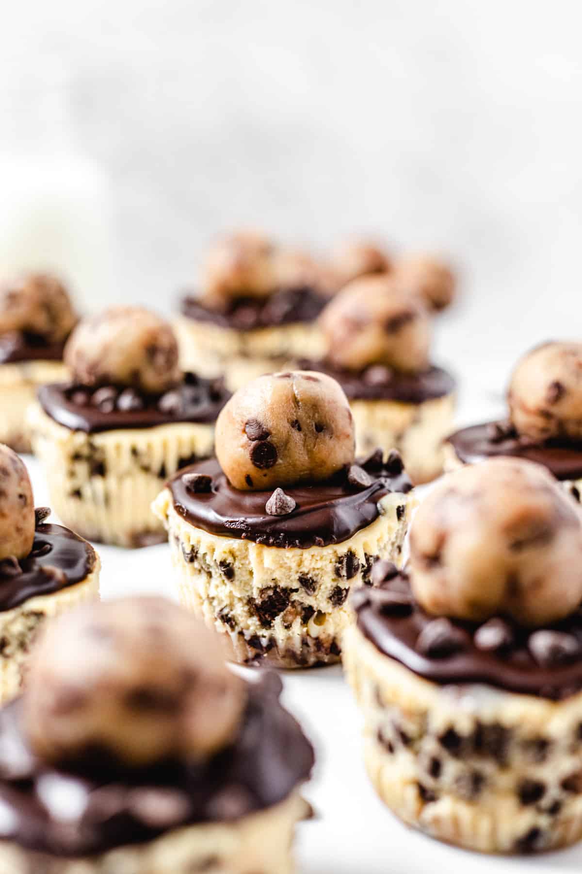 cookie dough topped cheesecake cupcake in the middle of many other cheesecakes