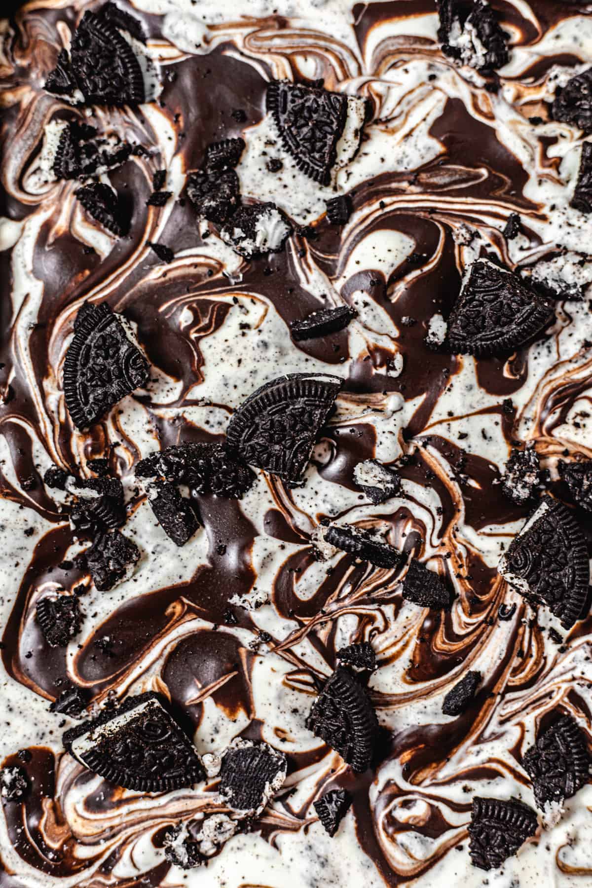 close up of the top of ice cream swirled with ganache and topped with Oreo pieces