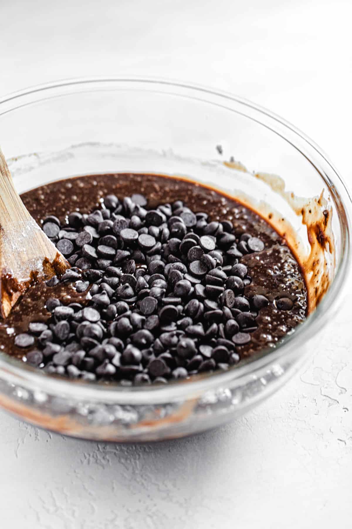 brownie batter with chocolate chips on top in a glass bowl