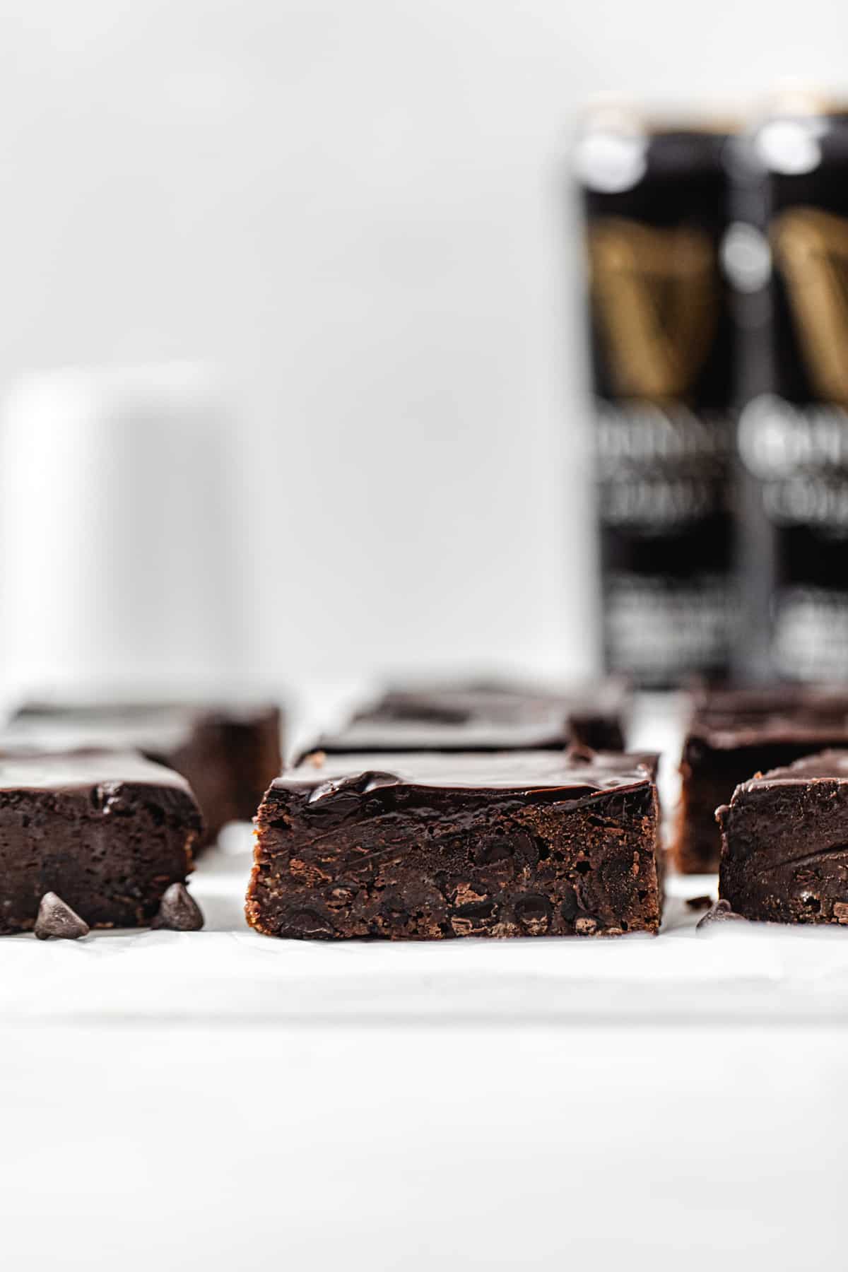 rows of brownies on parchment paper with 2 cans of Guinness beer in the background