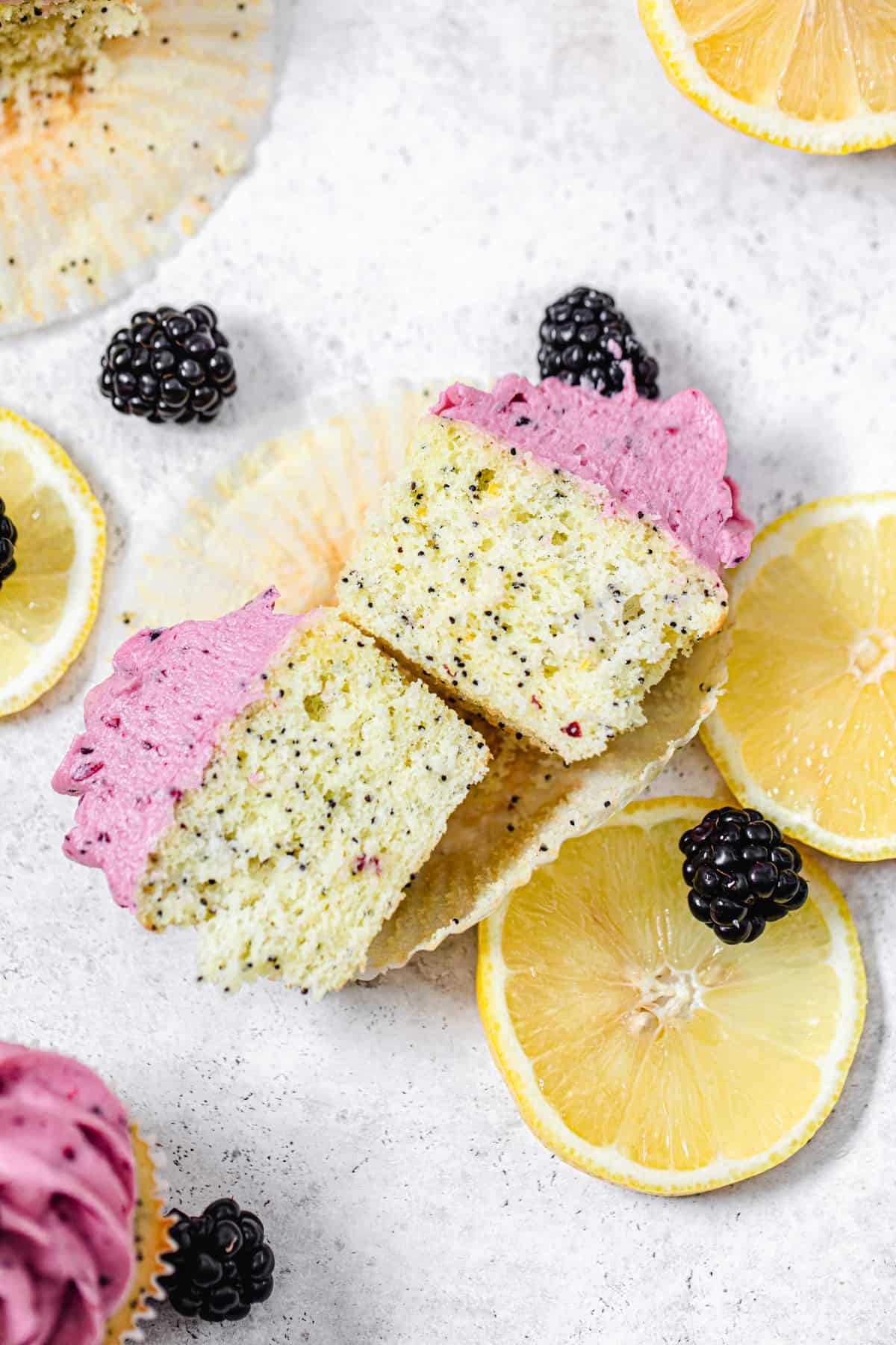 top view of halved cupcakes with lemon slices and fresh blackberries around them