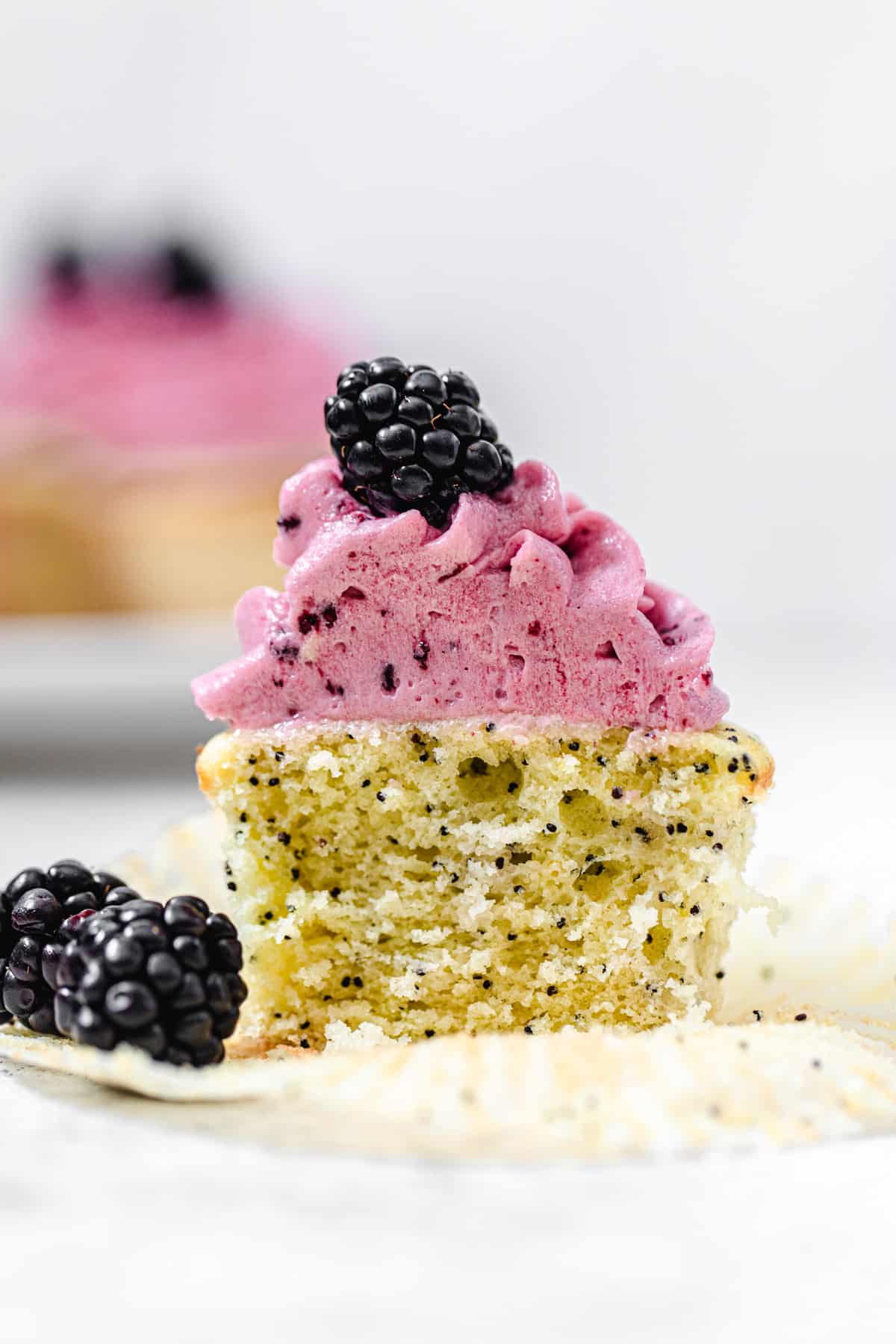 halved cupcake standing up on a cupcake wrapper with blackberries on it
