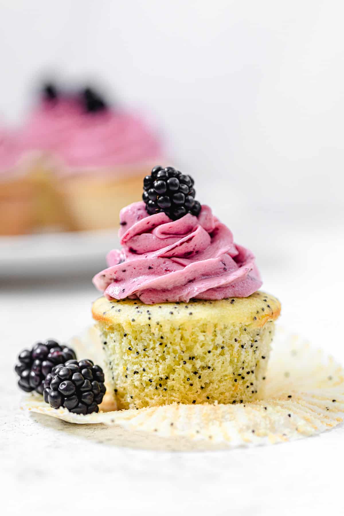 unwrapped cupcake with 2 blackberries next to it