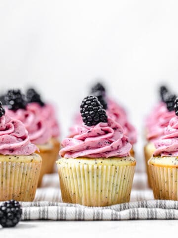 three rows of frosted cupcakes on a striped grey dish towel