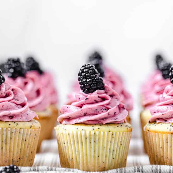 three rows of frosted cupcakes on a striped grey dish towel