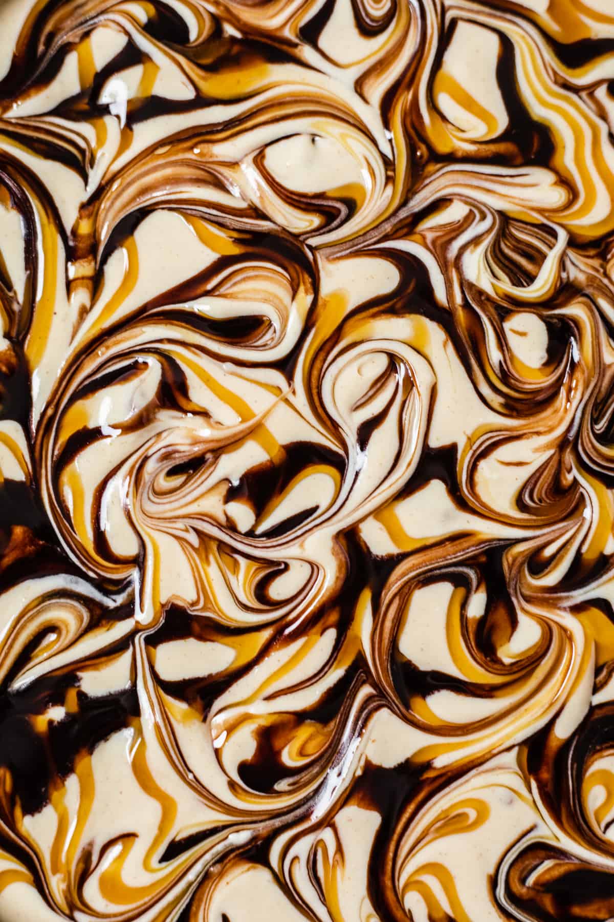 close up of caramel and chocolate sauce swirled cheesecake batter