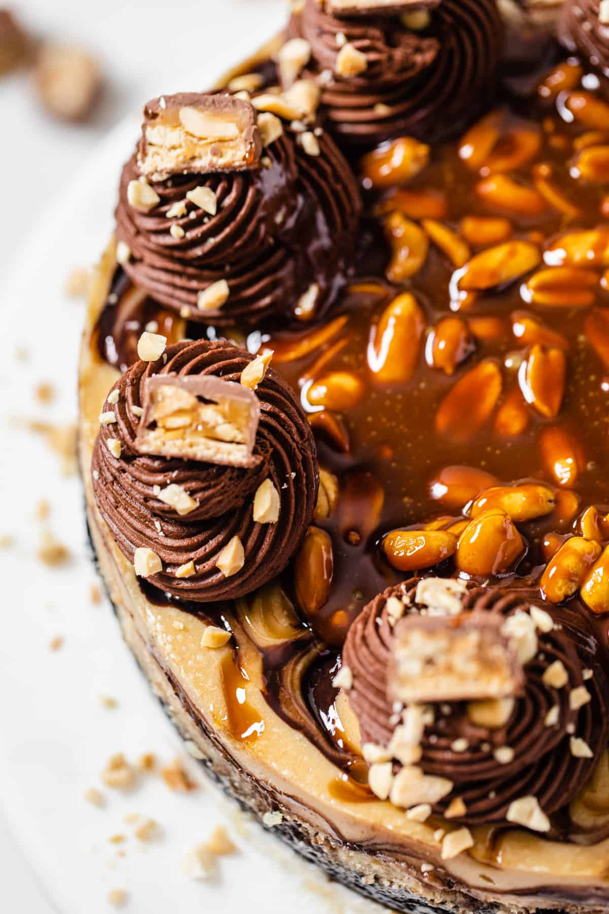 super close up of the whipped ganache frosting border topped with snickers and peanuts