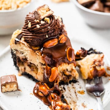 cheesecake slice on a white plate with a fork bite taken out of it