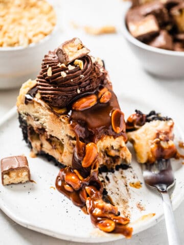 cheesecake slice on a white plate with a fork bite taken out of it