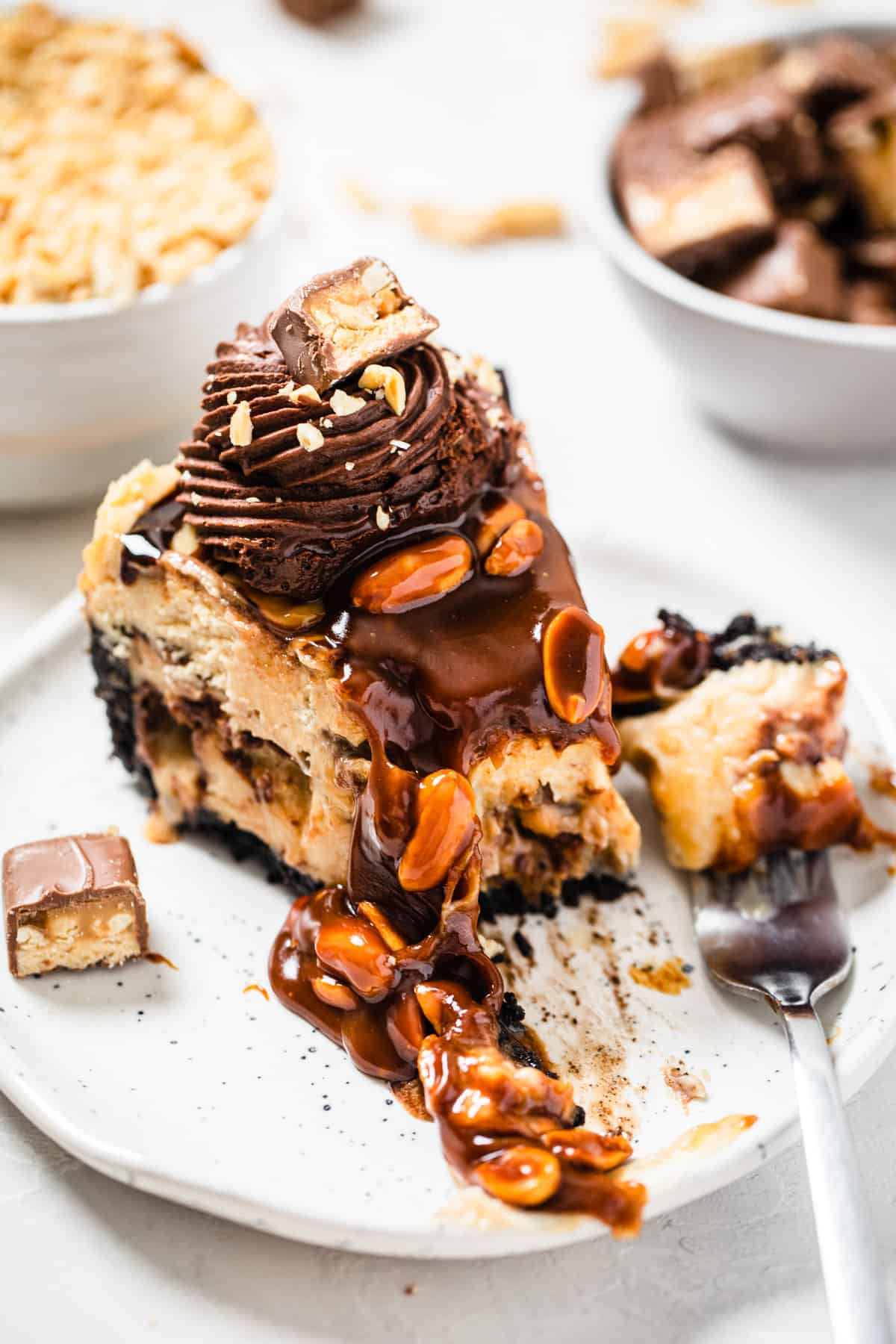 cheesecake slice on a white plate with a fork bite taken out of it