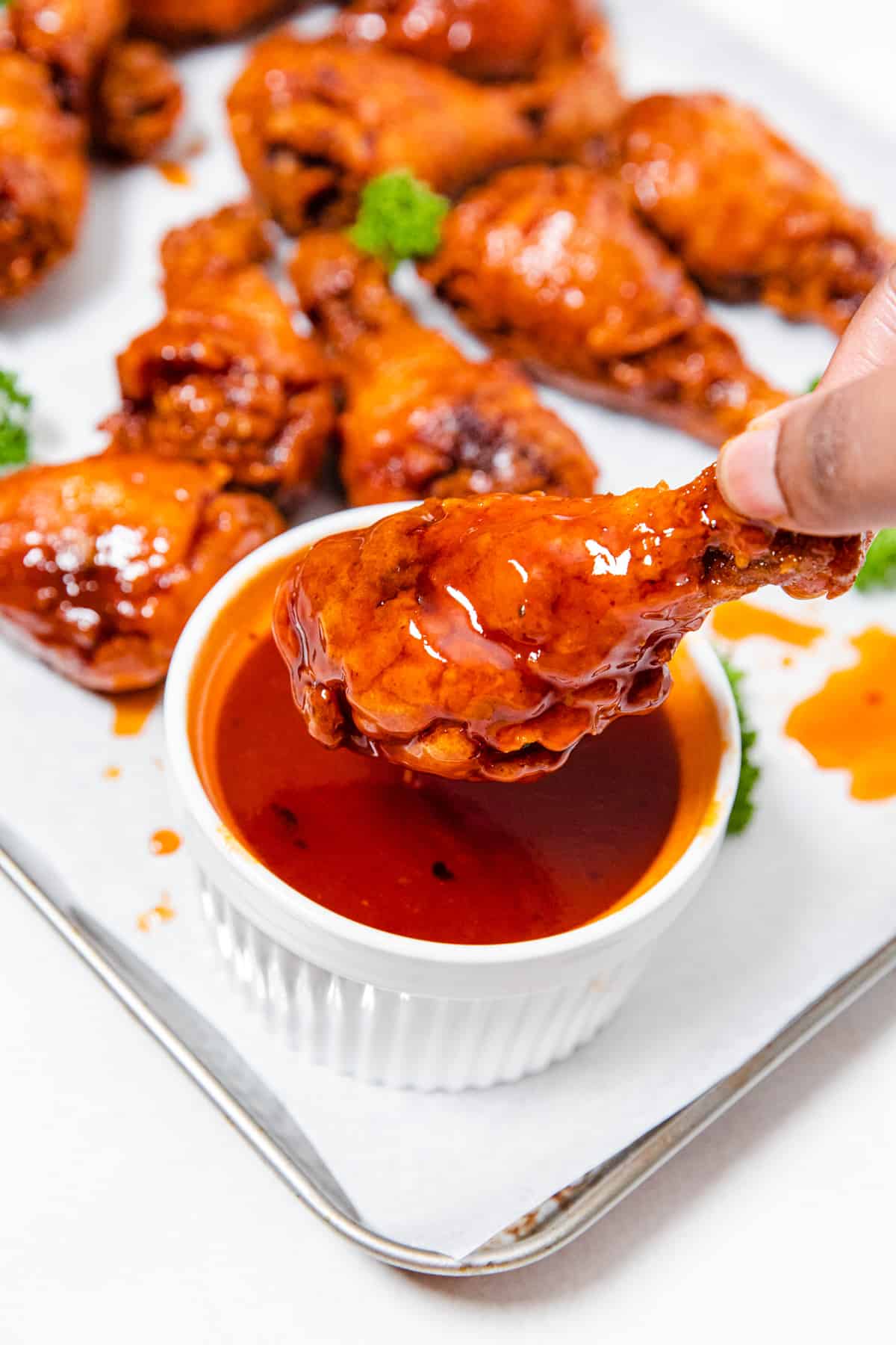 dipping a fried chicken drumstick into hot honey sauce